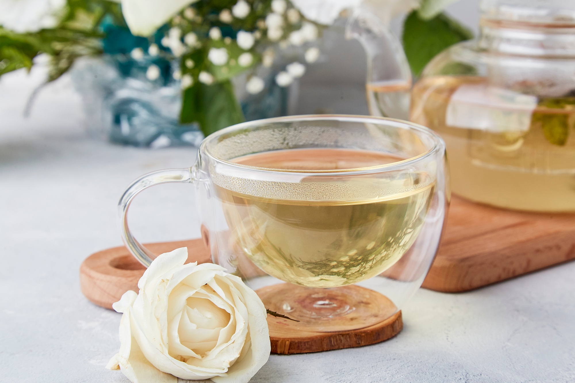 Herbal tea cup, aesthetic tea time in biophilic interior among white flowers.